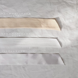 May include: Three different types of ribbon: natural cotton ribbon, white cotton ribbon, and white satin ribbon. The ribbons are labeled "baumwollband natur", "baumwollband wei&szlig;", and "seidenband".