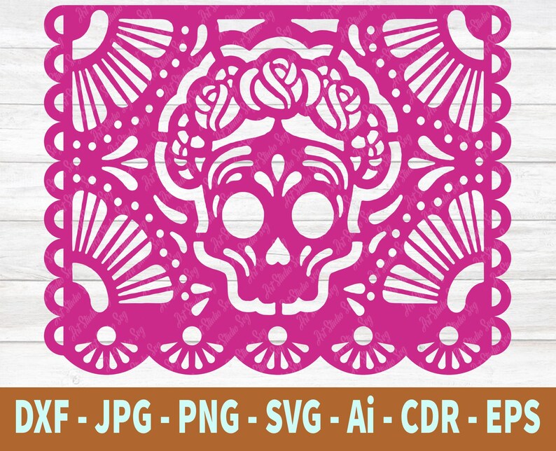 May include: A pink paper cutout of a sugar skull with floral details. The skull is surrounded by a decorative border with a repeating pattern.