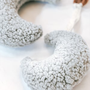 May include: Two gray plush crescent moon shaped baby teethers attached to a white and brown clip.