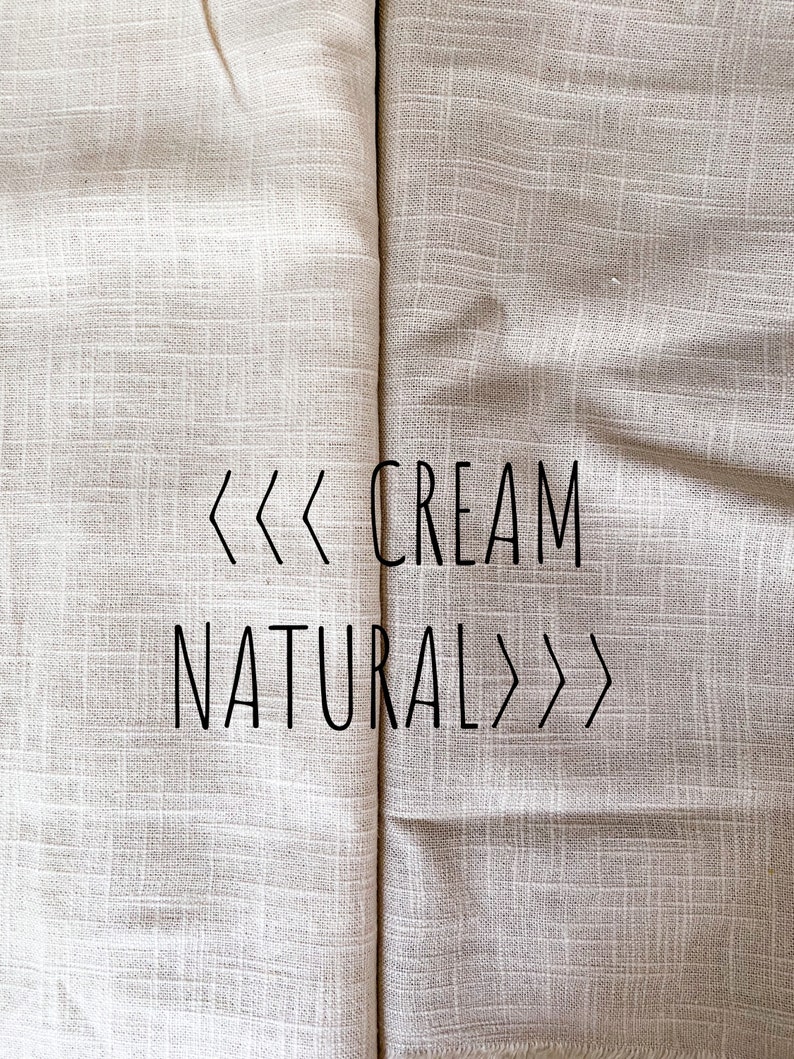 K&ouml;nnte beinhalten: Zwei Stoffmuster, eines cremefarben und eines naturfarben, nebeneinander. Der Stoff hat eine dezente gewebte Struktur. Der Text "<<< CREME NAT&Uuml;RLICH >>>" ist auf den Stoff gedruckt.