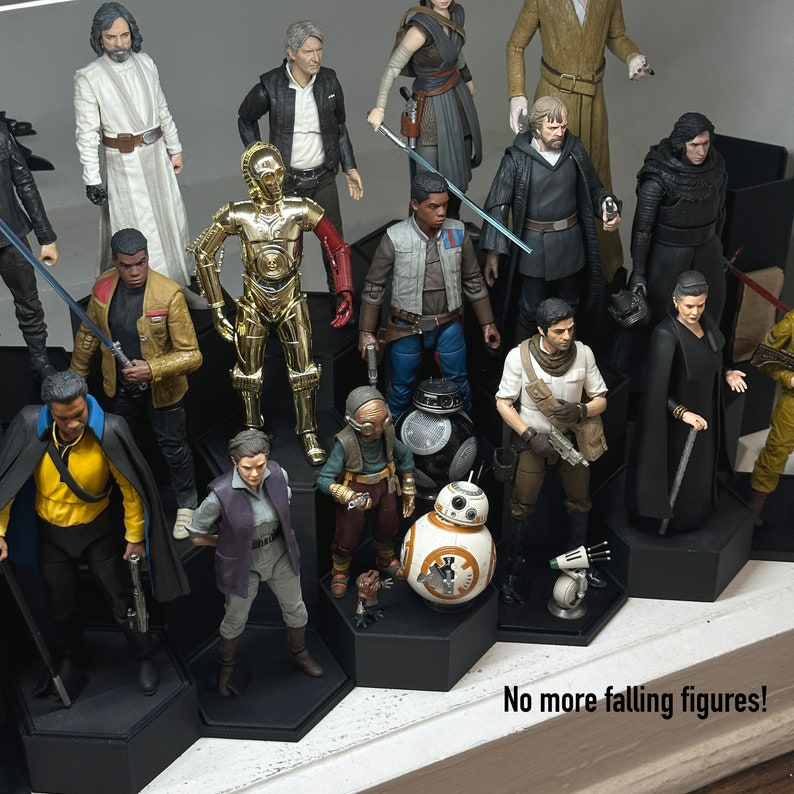 May include: A collection of Star Wars action figures displayed on a tiered stand. The figures include characters such as Luke Skywalker, Darth Vader, and Yoda. The stand is made of black plastic and has a tiered design. The figures are arranged in a variety of poses and are ready for display.