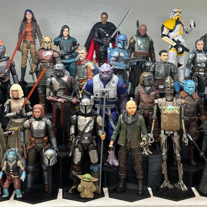 May include: A collection of Star Wars action figures, including characters such as Darth Vader, Yoda, and Stormtroopers. The figures are arranged in a display case, with some standing and others sitting. The figures are made of plastic and feature a variety of colours and details.