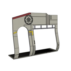 May include: A gray, geometric structure with a circular emblem and a rectangular opening. The structure has a dark red top and yellow accents. The base is a black, textured surface.