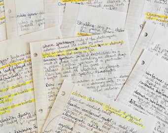 Puede incluir: Un conjunto de notas manuscritas en papel rayado, con texto resaltado en amarillo. Las notas cubren temas científicos, incluyendo espectroscopía atómica y mecánica cuántica. Las páginas están ligeramente arrugadas.