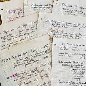 Puede incluir: Un conjunto de notas manuscritas en papel rayado, con conceptos y ecuaciones científicas. Las notas están en tinta negra y morada, con títulos como "Vaporización" y "Fuerza Dipolo". Los papeles están ligeramente arrugados.