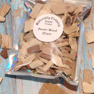 May include: A clear plastic bag filled with pecan wood chips. The bag has a white label that reads "Naturally Crabbby Organic Foraging Pecan Wood Chips".