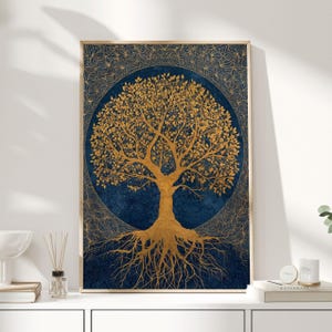 May include: A framed art print featuring a gold-colored tree design against a dark blue background. The tree has intricate details, with a circular pattern surrounding it. The artwork is displayed in a light-colored wooden frame, suitable for home decor.
