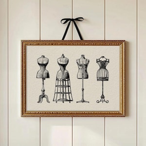 May include: A framed print featuring four vintage dress forms in black and white. The dress forms are displayed against a neutral background within a gold-colored frame, suspended by a black ribbon. The artwork evokes a classic, antique aesthetic.