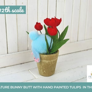 Op de afbeelding: Een miniatuur konijnenkontje figuur in een terracotta pot met handgeschilderde rode tulpen. De pot is gelabeld "1:12th scale" en "PATALUNIA Handmade Miniatures".