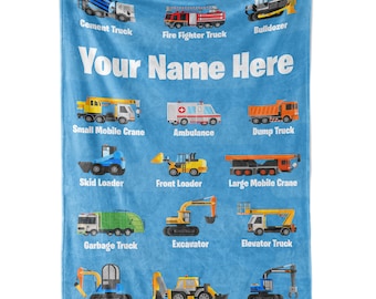 Puede incluir: Una manta de franela azul con ilustraciones coloridas de diferentes vehículos de construcción. Cada vehículo tiene una etiqueta debajo, como "Camión de cemento", "Camión de bomberos", "Bulldozer", "Grúa móvil pequeña", "Ambulancia", "Camión de volteo", "Cargador de orugas", "Cargador frontal", "Grúa móvil grande", "Camión de basura", "Excavadora", "Camión elevador", "Martillo neumático", "Cargadora retroexcavadora" y "Garra hidráulica". El texto "Your Name Here" está impreso en blanco en la parte superior de la manta.