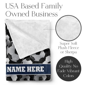 May include: A plush fleece blanket featuring a pattern of soccer balls in shades of gray and white on a black background. The blanket has a white, super soft plush fleece or sherpa backing. A navy blue band with the text "NAME HERE" is across the bottom.