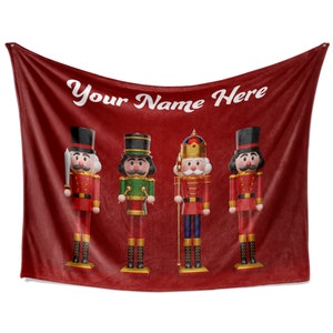 May include: Red fleece blanket with four nutcracker figurines. The blanket has the text "Your Name Here" printed on it.