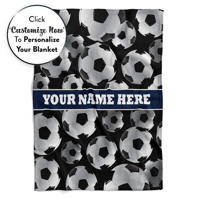 May include: A black blanket featuring a pattern of soccer balls in shades of gray and white. A navy blue banner across the blanket reads "YOUR NAME HERE" in white. The blanket also has the text "Click Customize Now To Personalize Your Blanket".