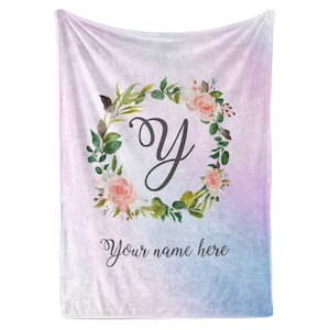 May include: A soft pink and blue ombre fleece blanket with a floral wreath and the letter "Y" in the center. The text "Your name here" is printed below the wreath.