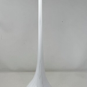 May include: A tall, white glass vase with a bulbous base and a long, slender neck. The vase has a marbled pattern of white and gray, and stands approximately 24 inches tall. This decorative vase is suitable for displaying flowers or as a standalone art piece.