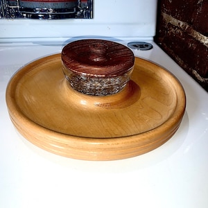 以下が含まれることがあります： 濃い茶色の蓋が付いた木製のボウル。ボウルは明るい木で作られており、滑らかな仕上がりです。蓋は暗い木で作られており、木目があります。