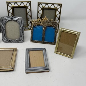 Op de afbeelding: Een assortiment van negen zilveren en gouden fotolijsten in verschillende maten en ontwerpen. Sommige lijsten hebben sierlijke details, terwijl andere eenvoudiger zijn. De lijsten zijn allemaal in goede staat en zouden een geweldige aanvulling zijn op elk interieur.