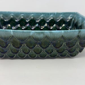 May include: A blue and green ceramic planter with a textured, scale-like design. The planter is rectangular and has a slightly rounded bottom.
