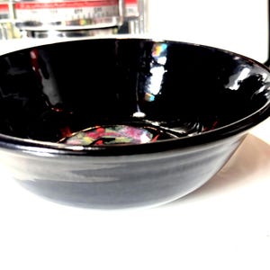 May include: A black ceramic bowl with a glossy finish. The bowl has a slight iridescent sheen, creating a rainbow effect in the light.