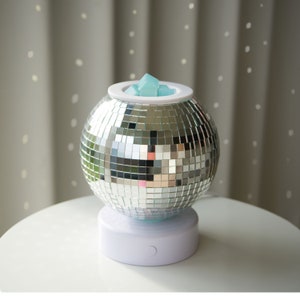 May include: A silver disco ball wax warmer with a white base and a blue wax melt inside.