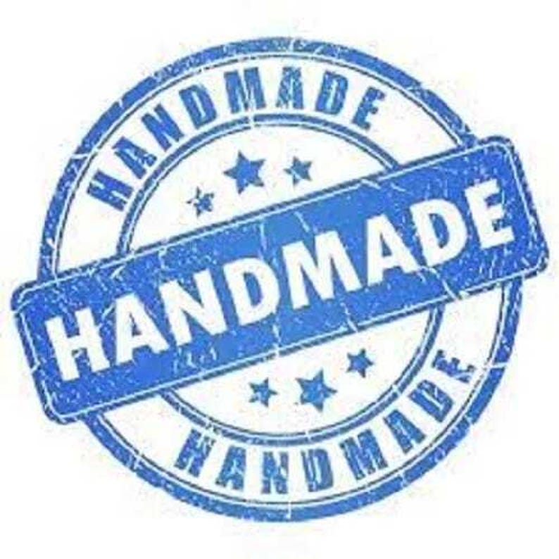May include: A blue and white distressed circle stamp with the word "HANDMADE" in bold white letters. The word "HANDMADE" is repeated around the outer edge of the circle.