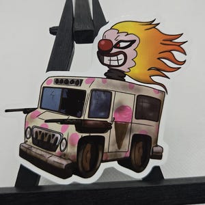 May include: A sticker featuring a cartoon ice cream truck with a menacing clown on top. The truck is white with pink polka dots and a pink ice cream cone graphic. The clown has red eyes, a red nose, and yellow and orange hair.