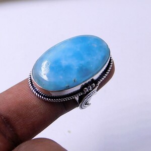 May include: A silver ring with a large oval blue gemstone. The ring has a decorative band with a crescent moon design.