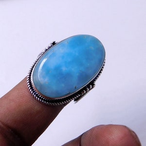 May include: A silver ring with a large oval blue gemstone. The gemstone has a cloudy, marbled appearance.