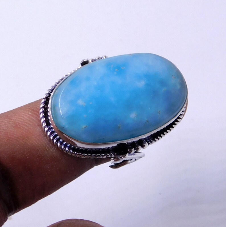 May include: A silver ring with a large oval blue gemstone. The ring has a twisted band design.