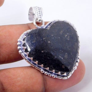 Pu&ograve; includere: Un ciondolo a forma di cuore in argento con una pietra preziosa nera. Il ciondolo ha un bordo argentato dettagliato con piccole perle.