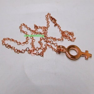 May include: A rose gold necklace with a heart-shaped chain and a pendant in the shape of the female symbol.