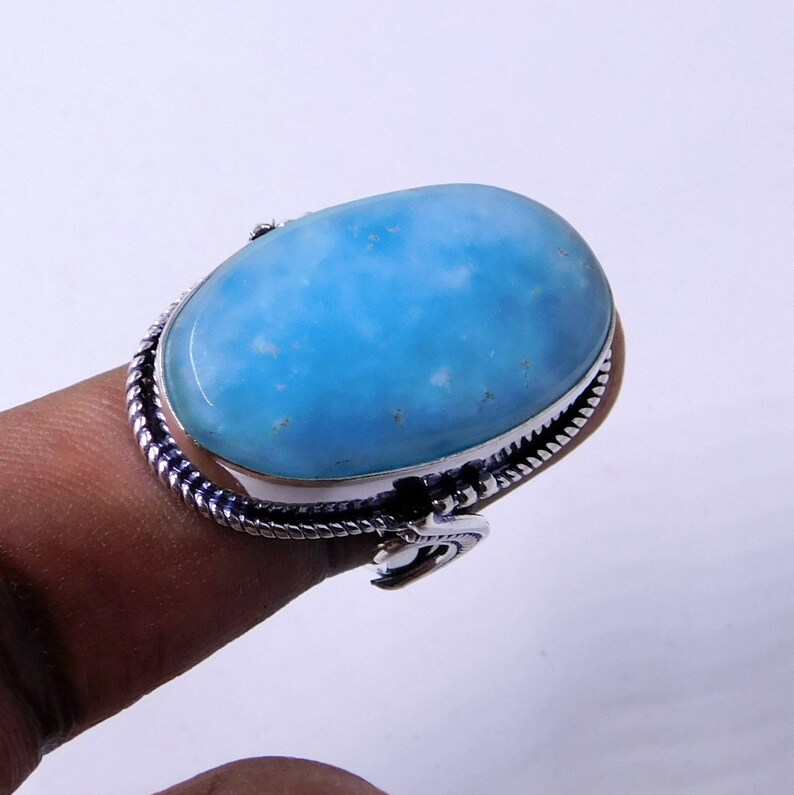 May include: A silver ring with a large oval blue gemstone. The ring has a twisted band design.