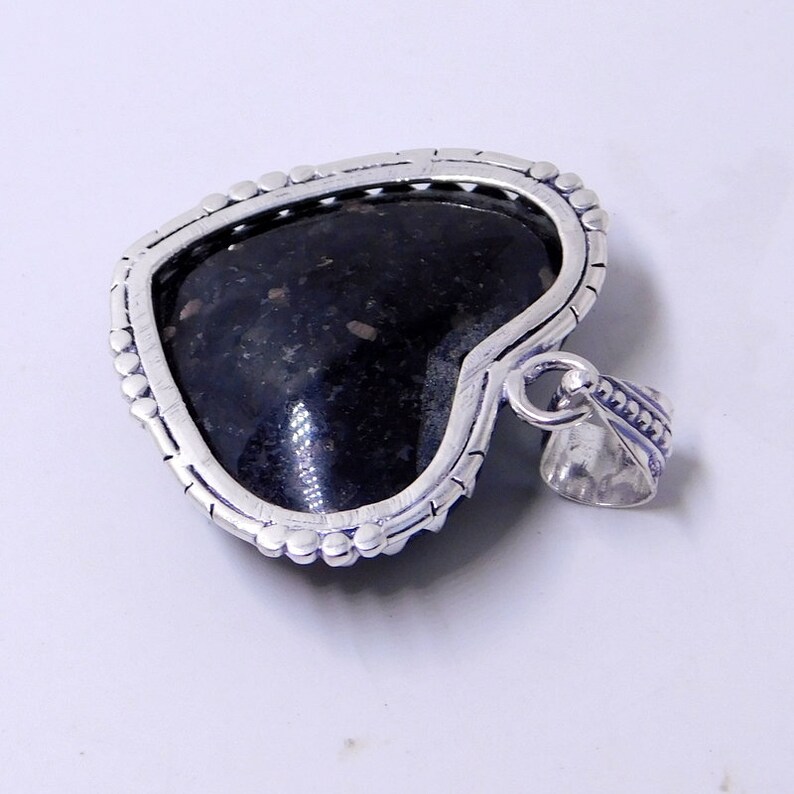Pu&ograve; includere: Un ciondolo a forma di cuore in argento con una pietra nera incastonata al centro. Il ciondolo ha un bordo dettagliato e un'anellina per attaccare una catena.
