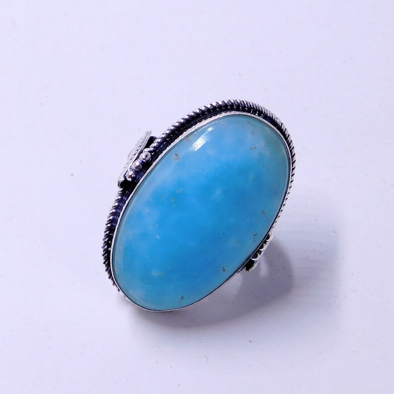 May include: A silver ring with a large oval blue gemstone. The ring has a detailed silver band.
