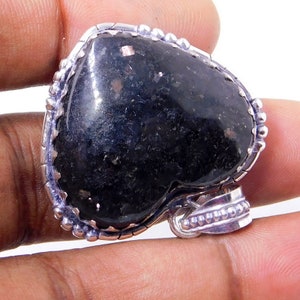 Pu&ograve; includere: Un ciondolo a forma di cuore in pietra nera con accenti argentati. Il ciondolo &egrave; incastonato in una cornice d'argento con un bordo perlato. La pietra preziosa ha un aspetto maculato.