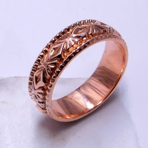 Peut inclure: Une bague en or rose avec un motif géométrique. La bague est en métal et a une finition lisse et polie.