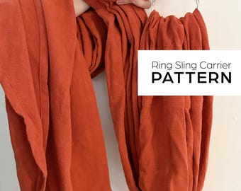May include: A rust-colored fabric ring sling carrier with silver rings. The fabric is folded and gathered around the rings. The text "Ring Sling Carrier PATTERN" is printed in black on a white rectangle.