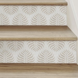 May include: Close-up of wooden stairs with a beige and white patterned wallpaper on the risers. The pattern features a repeating design of stylised leaves.