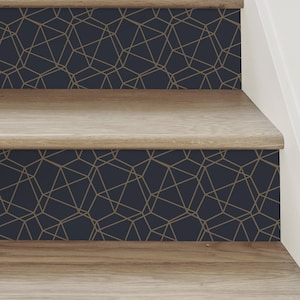 May include: Close-up of wooden stairs with a geometric pattern wallpaper on the risers. The wallpaper is navy blue with gold lines forming a repeating pattern of geometric shapes.