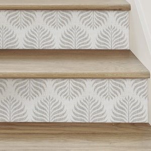 May include: Close-up of a set of wooden stairs with a grey and white patterned wallpaper on the risers. The pattern features a repeating design of stylised leaves.