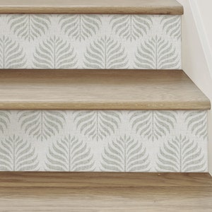 May include: Wooden stairs with a light grey and white patterned wallpaper with a leaf design. The wallpaper is on the bottom edge of each stair tread.