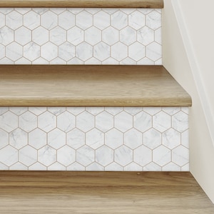 Puede incluir: Hileras de peldaños de escalera de baldosas hexagonales de mármol blanco con líneas de lechada doradas. Las baldosas se aplican a escaleras de madera.