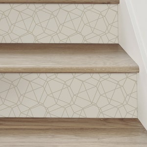 May include: Wooden staircase with geometric patterned risers. The steps are made of light brown wood, and the risers feature a beige background with a gray geometric design. The staircase is against a white wall.