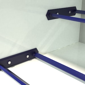 May include: Two blue metal shelf supports with screws attached to a white wall. The supports are designed to hold shelves in place.