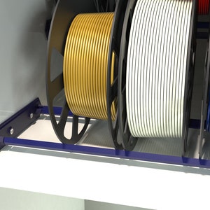May include: A close-up of a spool rack with three spools of filament. The filament is yellow, white, and blue. The rack is made of metal and has a blue finish.
