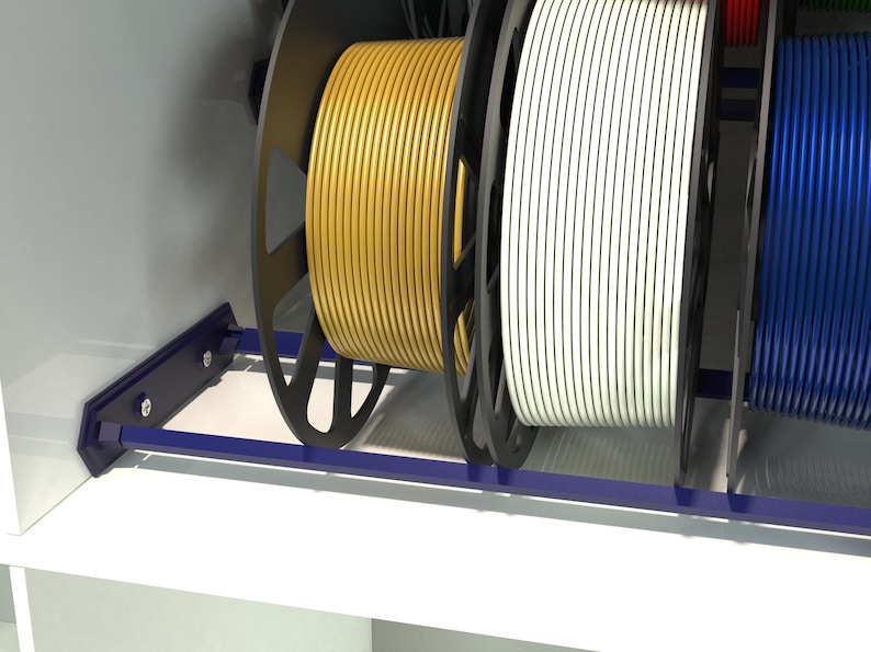 May include: A close-up of a spool rack with three spools of filament. The filament is yellow, white, and blue. The rack is made of metal and has a blue finish.