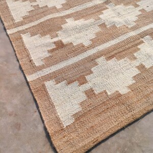 May include: A brown and white woven rug with a geometric pattern. The rug has a natural, rustic look and feel.