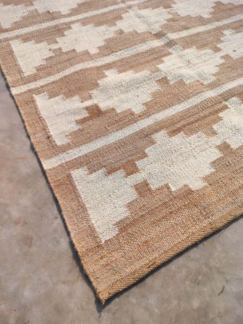 May include: A brown and white woven rug with a geometric pattern. The rug has a natural, rustic look and feel.