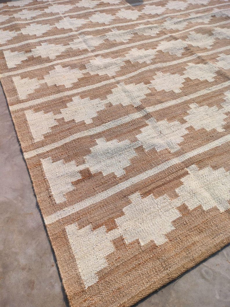 May include: A brown and white woven rug with a geometric pattern. The rug has a natural, earthy feel and would add a touch of texture to any room.