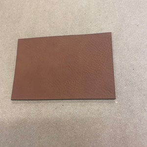 May include: A close-up of a brown leather swatch. The leather has a textured surface.